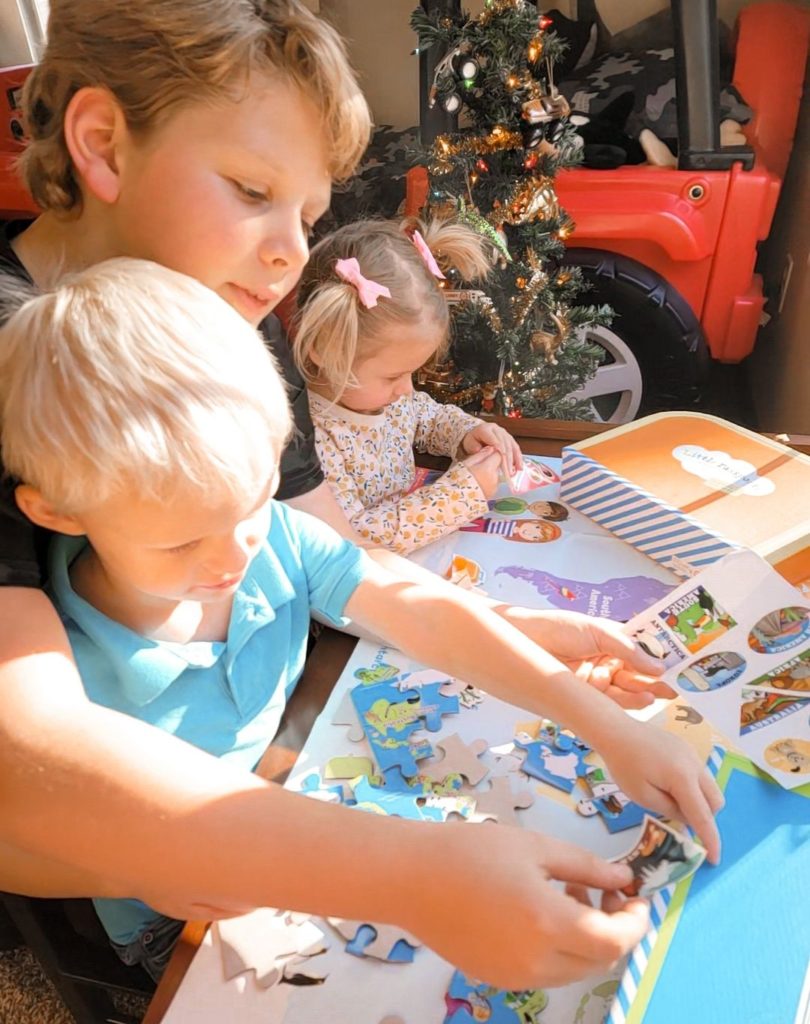 three children playing with travel themed puzzle from Little Passports