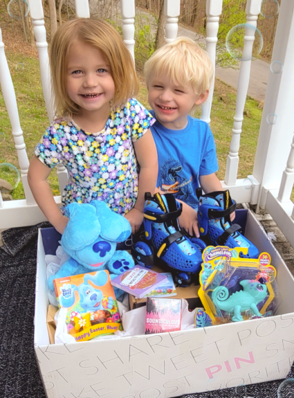 two kids sitting behind large box of toys