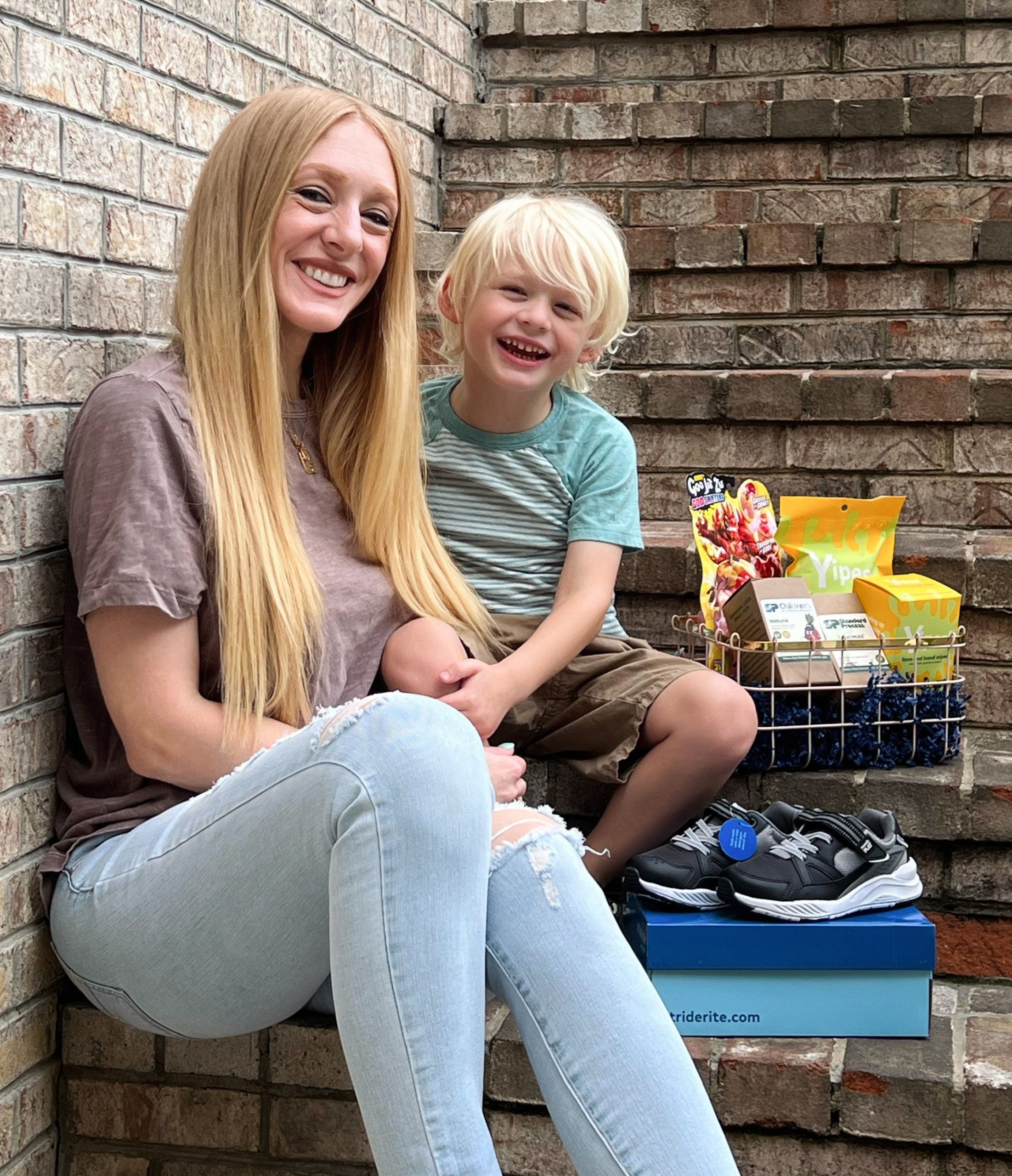 mom and son sitting on stairs with back to school items next to them