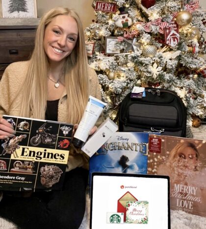 girl sitting with various gifts around a tree