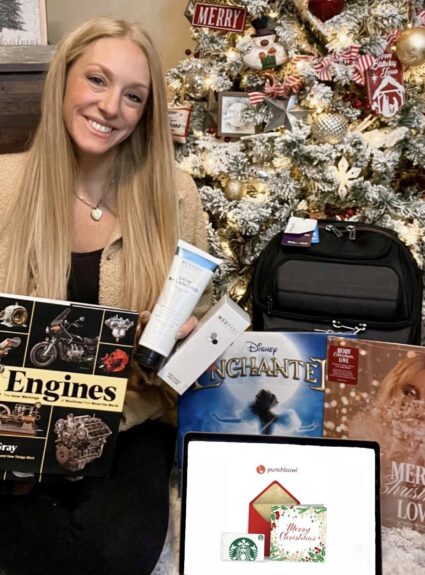 girl sitting with various gifts around a tree